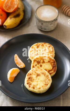 Petit déjeuner végétarien de quark des crêpes au miel, de fruits et de café avec du lait. Style rustique. Banque D'Images
