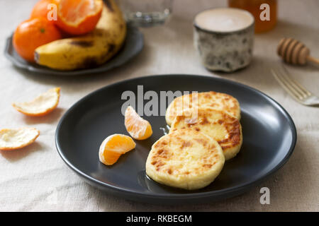 Petit déjeuner végétarien de quark des crêpes au miel, de fruits et de café avec du lait. Style rustique. Banque D'Images