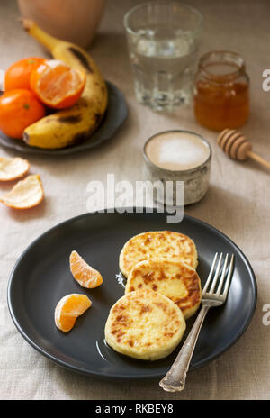 Petit déjeuner végétarien de quark des crêpes au miel, de fruits et de café avec du lait. Style rustique. Banque D'Images