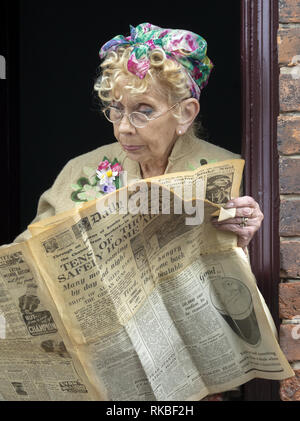 Femme en costume reading newspaper à 1940 week-end au Black Country Living Museum de Dudley, West Midlands, England, UK Banque D'Images