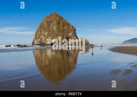 Les touristes et les habitants profitant de la plage avec en arrière-plan, Haystack Rock at Cannon Beach, Oregon, USA. Banque D'Images