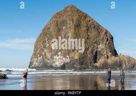 Un couple d'adultes prendre une photo avec le téléphone à un jeune couple avec Haystack Rock en arrière plan à Cannon Beach Banque D'Images