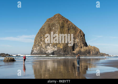 Un couple d'adultes prendre une photo avec le téléphone à un jeune couple avec Haystack Rock en arrière plan à Cannon Beach Banque D'Images