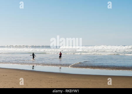 Un jeune couple jouer pour échapper à la vague qui vient de prendre à Cannon Beach, Oregon, USA. Banque D'Images