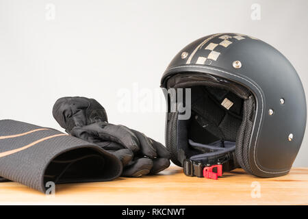 L'équipement de protection moto - face ouverte casque, gants et une ceinture sur un fond de bois. Banque D'Images