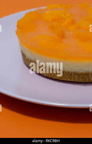 Mandarin Orange gâteau au fromage sur une plaque rose sur fond orange Banque D'Images