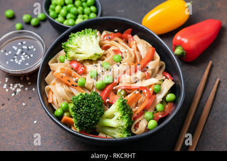 Sauté de nouilles asiatiques avec des légumes dans un bol. Les nouilles Udon avec le brocoli, le poivron, la carotte et les petits pois verts Banque D'Images