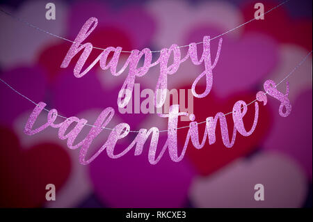 Bonne Saint Valentin message dans glitter script pendants devant un fond abstrait de recentré entend Banque D'Images