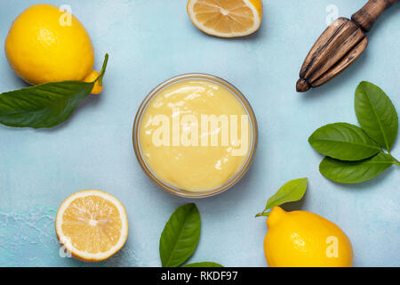 Bol en verre en kurde de citron, citrons frais sur fond bleu. Vue de dessus Banque D'Images