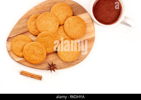 Un gros plan des cookies au gingembre avec une tasse de chocolat chaud, un bâton de cannelle, et une étoile d'anis, tourné par le haut sur un fond blanc Banque D'Images
