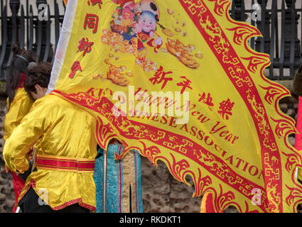 Homme porte un grand drapeau chinois jaune de l'Association chinoise, qui souhaite une Bonne Année à la Parade à Londres, au Royaume-Uni. Banque D'Images