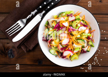 Salade de légumes végétarien sain avec des matières premières fraîches radis, carotte, céleri, laitue, de sésame et de graines de lin. Alimentation nourriture Vegan Banque D'Images