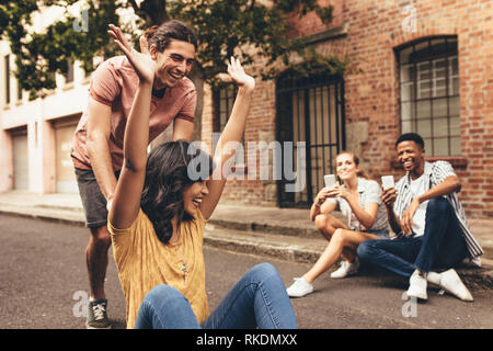 Groupe d'amis en créant de nouveaux contenu des médias sociaux à l'extérieur. Les jeunes à prendre des photos avec des téléphones portables de couple sur planche sur cit Banque D'Images