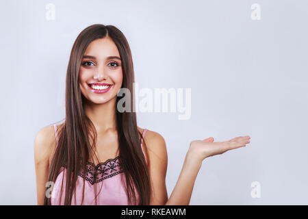 Temps de vente, remises pour le 14 février, nice, cute brunette woman showing copy space sur sa paume, looking at camera, debout sur fond gris Banque D'Images