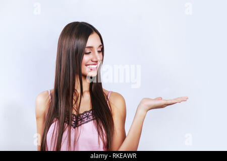 Temps de vente, remises pour le 14 février, nice, cute brunette woman showing copy space sur sa paume, à la recherche à l'autre, debout sur fond gris Banque D'Images