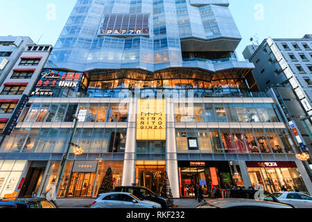 Tokyo, Ginza. Heure d'or. Kirarito Ginza, high end 12 centre commercial bâtiment avec des arbres de Noël à l'extérieur sur la chaussée. La circulation en premier plan. Banque D'Images