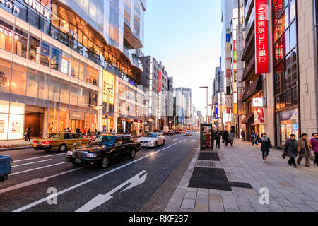 Tokyo, Ginza. Heure d'or. Afficher le long de rue avec Kirarito Ginza, high end 12 centre commercial bâtiment avec des arbres de Noël à l'extérieur sur la chaussée. Banque D'Images