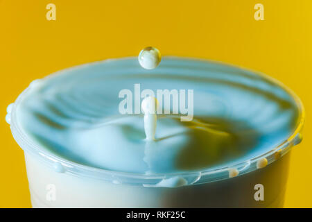 Photographie à haute vitesse d'une goutte de lait sur fond jaune dans le studio Banque D'Images