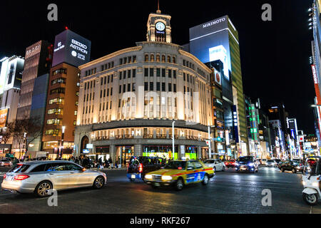 Tokyo, Ginza, nuit. 4-chome intersection avec le trafic et les taxis qui passent, flou de mouvement, et en arrière-plan l'Wako Department store et d'autres. Banque D'Images