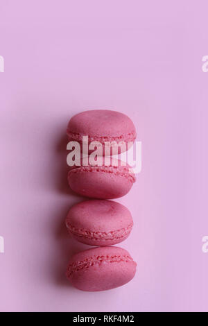 Quatre macarons rose sur un fond rose clair, vertical Banque D'Images