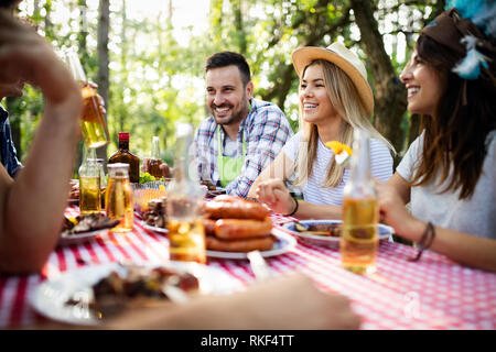 Groupe d'amis heureux de manger et boire des bières à dîner barbecue Banque D'Images