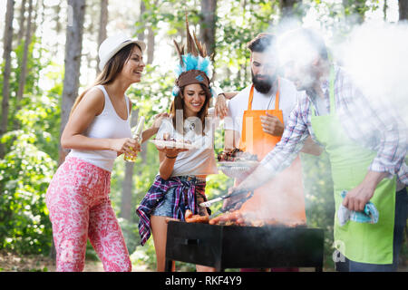 Groupe d'amis heureux de manger et boire des bières à dîner barbecue Banque D'Images