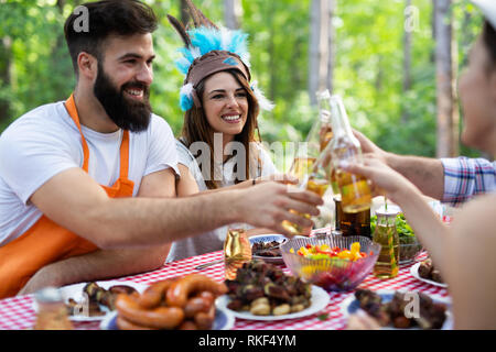 Groupe d'amis heureux de manger et boire des bières à dîner barbecue Banque D'Images