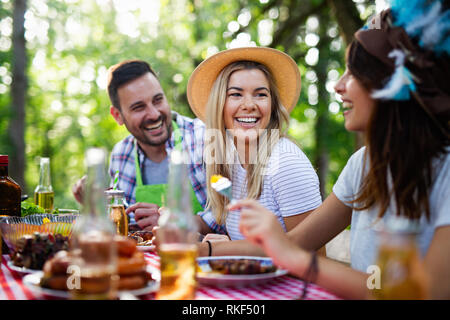 Groupe d'amis heureux de manger et boire des bières à dîner barbecue Banque D'Images