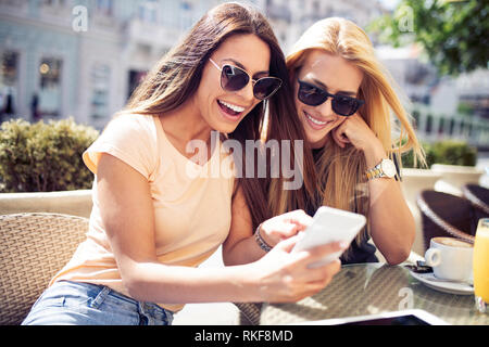 Belles filles s'amusant smiling together in a cafe outdoor Banque D'Images