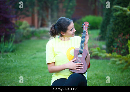 Cute girl jouant son ukulele en plein air dans la soirée Banque D'Images