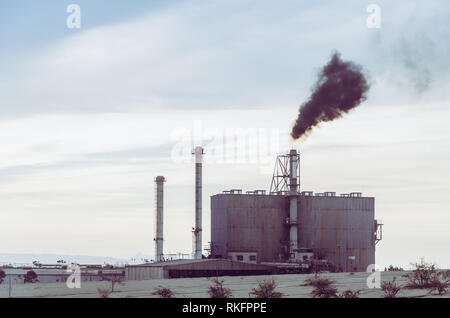 Une usine souffle la fumée dans le ciel pendant la matinée. Banque D'Images