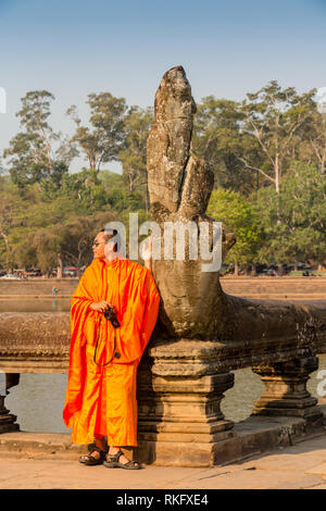 Le moine bouddhiste portant des robes safran, utilise les technologies les plus récentes sur son téléphone mobile, Ta Prohm, Angkor Wat, Siem Reap, Cambodge Banque D'Images