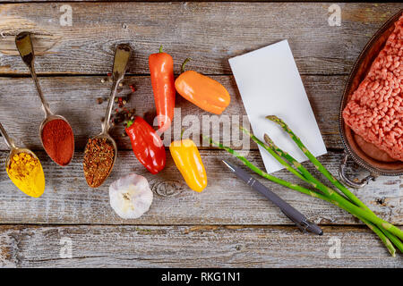 Préparation de la farce poivrons colorés avec des ingrédients : viande hachée, l'assaisonnement et vert frais contenant de fer sur fond de table rustique Banque D'Images