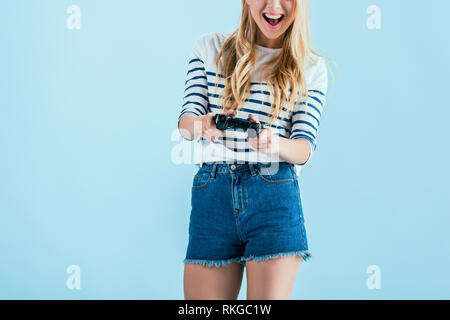 Portrait de jeune femme en riant avec gamepad isolé sur blue Banque D'Images