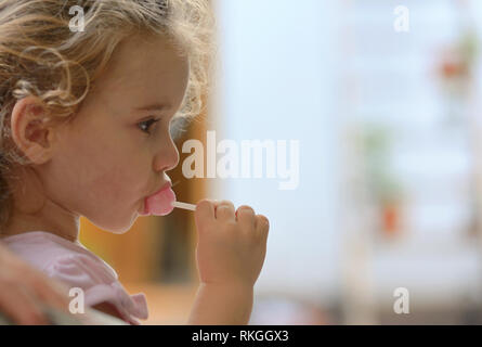 Little girl eating a pink lolly pop Banque D'Images