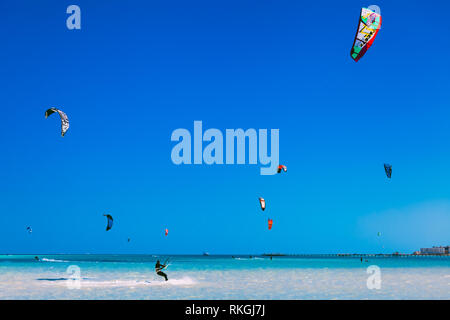 L'Egypte, Hurghada - 30 novembre, 2017 : de nombreux cerfs-volants de vol dans le ciel bleu au-dessus de la surface de la mer. Le professionnel des kitesurfers et glisse sur les vagues Banque D'Images