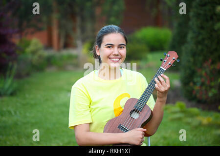 Cute girl jouant son ukulele en plein air dans la soirée Banque D'Images