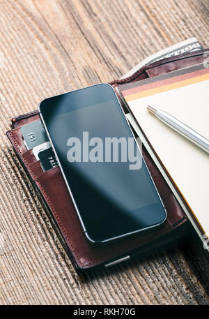 Smartphone avec écran vide, porte-monnaie, billets de dollar, les cartes de crédit et de débit portable sur table en bois. Vue de dessus. Orientation portrait Banque D'Images