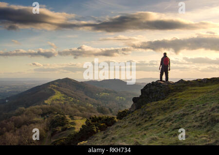 Un randonneur solitaire au sommet d'une colline avec vue sur la crête des collines de Malvern, en Angleterre. Sous le soleil d'hivers jour au coucher du soleil. Banque D'Images