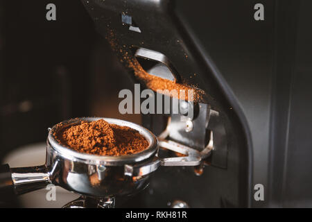 Le broyage à l'aide de grains de café barista, machine à café, moulin à café fraîchement torréfié haricots faire broyer en une poudre. Banque D'Images