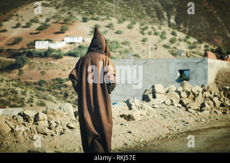 Un homme portant une tenue appelée une djellaba ou thoub promenades le long du bord de la route juste à l'extérieur de la ville de Chefchaouen. Banque D'Images