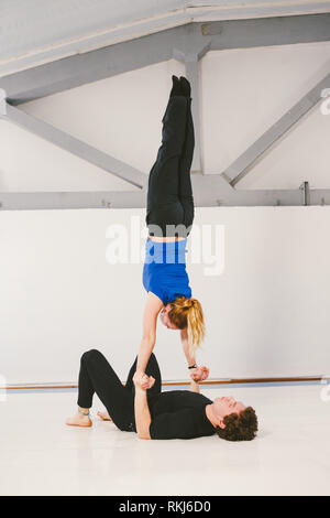 Thème est le sport et la superficie. Un jeune homme de race blanche et de sexe féminin couple practicing yoga acrobatique dans un livre blanc sur les tapis de sport. Un homme s'allonge sur le dos et jours fériés Banque D'Images