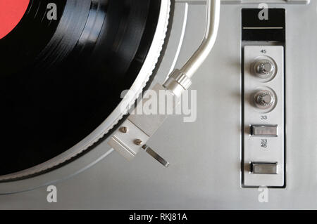 Vintage turntable en cas d'argent avec des boutons et des boutons sur le tableau de contrôle avec un disque vinyle avec étiquette rouge studio shot vue supérieure Banque D'Images