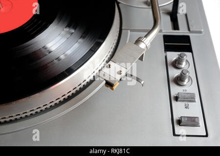 Vintage turntable en cas d'argent avec des boutons et des boutons sur le tableau de contrôle avec un disque vinyle avec étiquette rouge isolé sur fond blanc. Vue de dessus fermer Banque D'Images