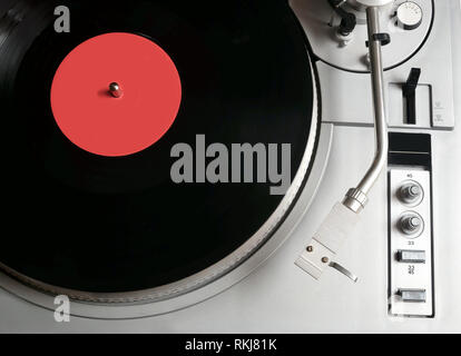 Vintage turntable en cas d'argent avec des boutons et des boutons sur le tableau de contrôle avec un disque vinyle avec étiquette rouge studio shot vue supérieure Banque D'Images