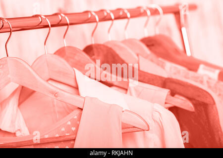 Coral womens vêtements sur cintres en bois sur une grille dans un magasin de mode. penderie, blouses robes femmes close up Banque D'Images