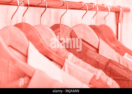 Coral womens vêtements sur cintres en bois sur une grille dans un magasin de mode. penderie, blouses robes femmes close up Banque D'Images