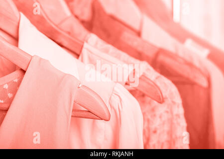 Coral womens vêtements sur cintres en bois sur une grille dans un magasin de mode. penderie, blouses robes femmes close up Banque D'Images