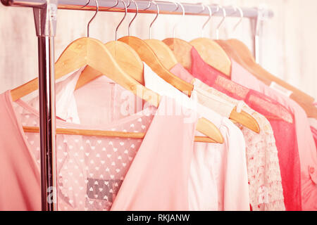 Coral womens vêtements sur cintres en bois sur une grille dans un magasin de mode. . Les femmes robes, blouses, penderie Banque D'Images