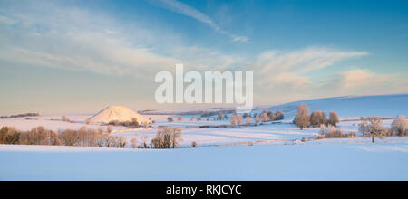 Silbury Hill dans la neige de l'hiver au lever du soleil. Avebury, Wiltshire, Angleterre. Vue panoramique Banque D'Images